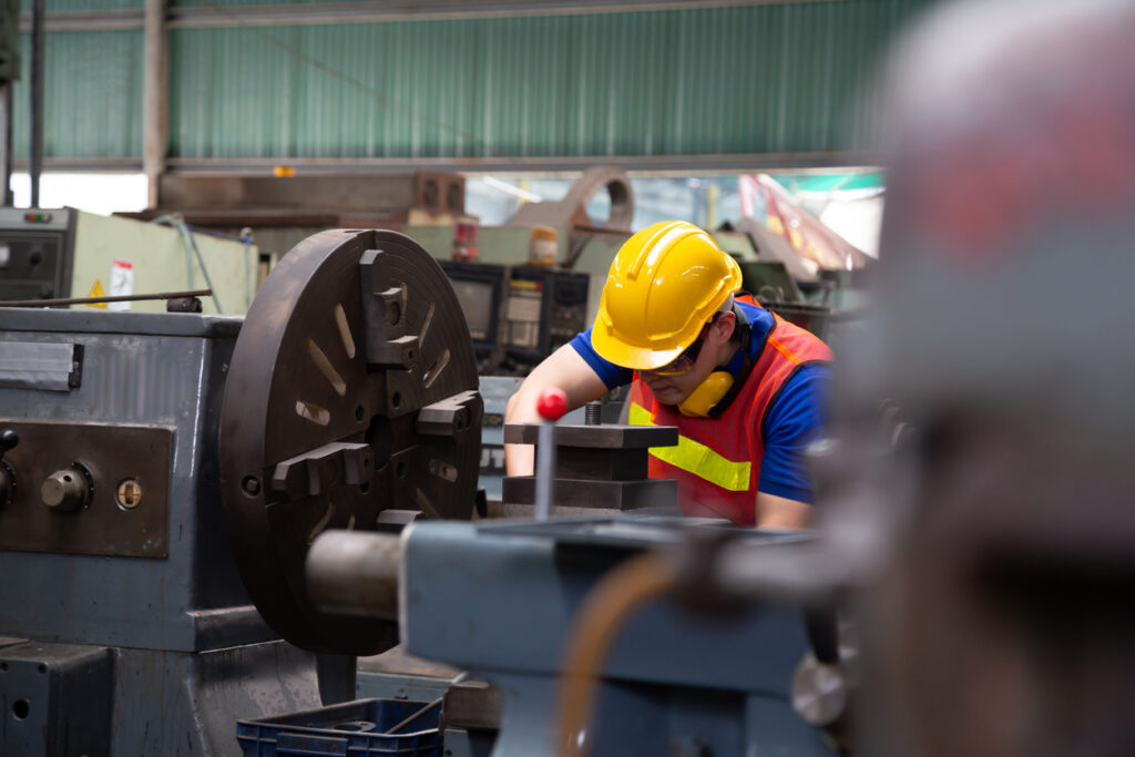 Worker using machinery in an industrial setting for assembly coordination