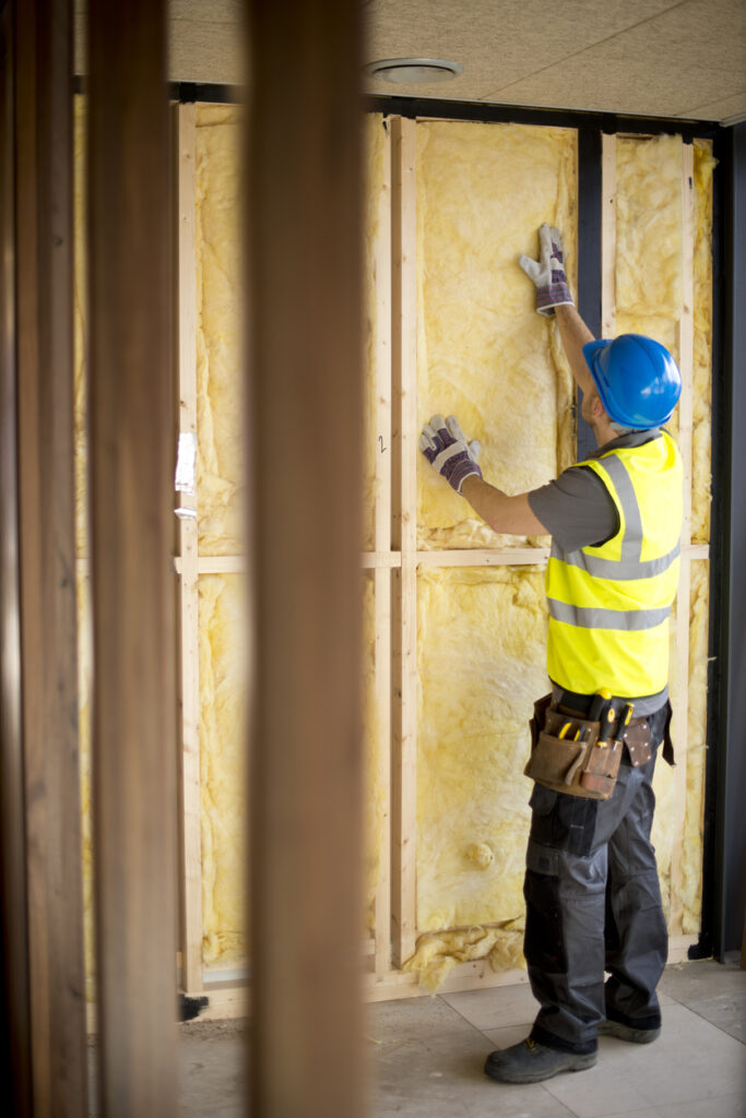 Worker installing insulation to reduce noise transmission